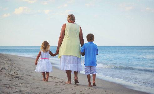 快乐祖母与孩子小男孩和女孩在海滩