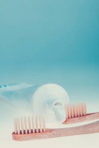 两个米色的牙科画笔附近的蓝白色背景上的牙膏管。孤立。健美的照片