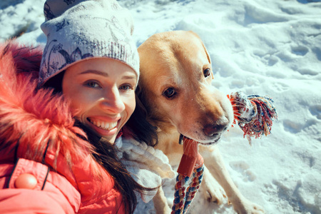 女人与狗拉布拉多犬在冬天的户外玩