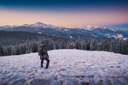 徒步旅行者站在一座小山与雪