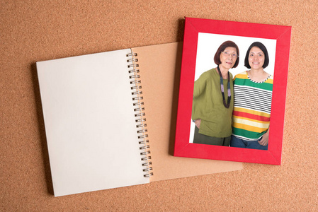 笔记本和框架与妈妈和女儿上木制的图片