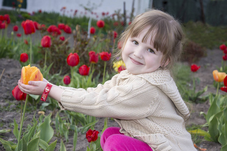 春天在花园里坐着, 微笑着的小女孩拿着一个 t