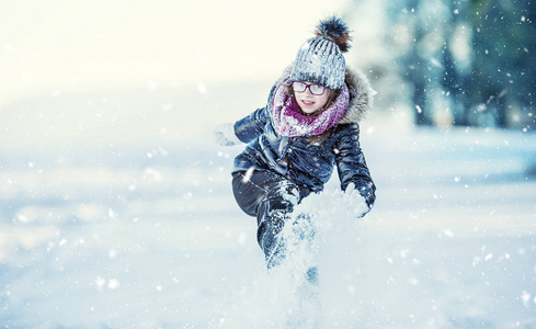 年轻的女孩正在玩雪。美冬天快乐女孩吹雪在寒冷的冬季公园或户外。女孩和冬季寒冷的天气