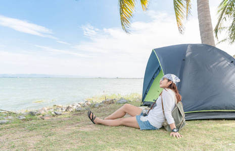 时髦的旅行者女人放松与帐篷上坝的位置