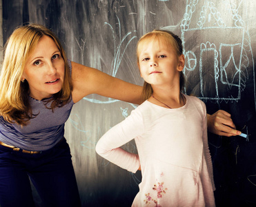 成熟的女人老师和小可爱的金发女孩学生写在黑板上在一起，生活方式的人概念的肖像