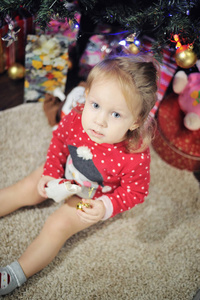 可爱的小女孩坐在反对圣诞节装饰