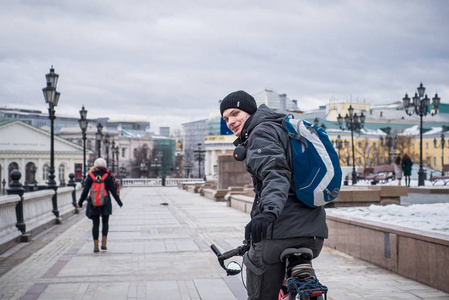 一个年轻人在一件温暖的外套和帽子上一辆自行车在莫斯科中心在冬天