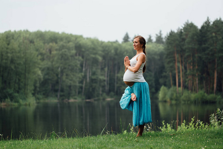 孕妇瑜伽产前产假做不同的练习。在公园上的草 呼吸 拉伸 静力学