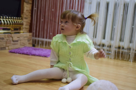 一岁的女婴坐在地板上。 一个玩柳条球的孩子。 一个金发女孩。