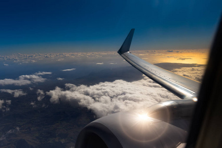 从飞机窗口查看在日出或日落时。云背景上方飞行飞机机翼