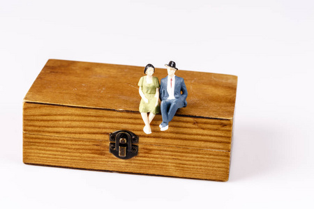 玩具模型老夫妇坐在木制的盒子