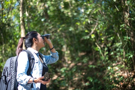 旅行者女人看起来对森林的双筒望远镜