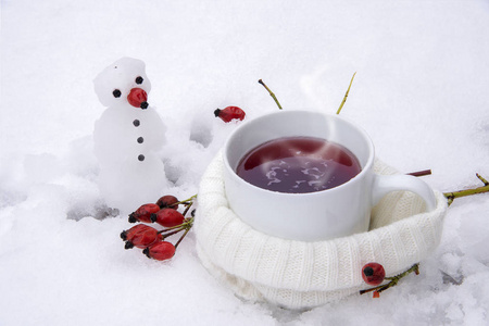 红玫瑰果在雪地里一个小雪人，预防流感冬天喝热茶