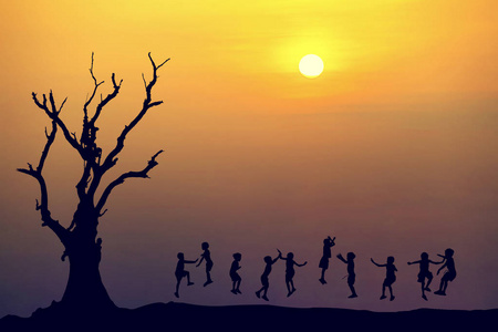 快乐儿童跳在日落时的剪影