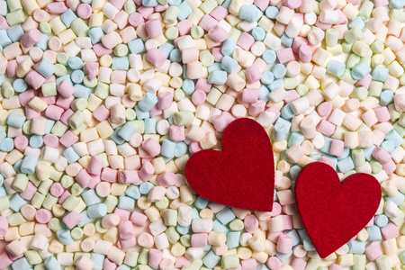 两个红色的心，在多彩的迷你棉花糖背景