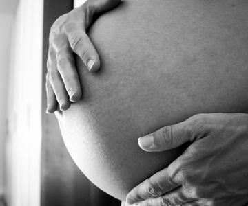 黑白照片的一名怀孕的妇女，爱抚着她自己的肚子