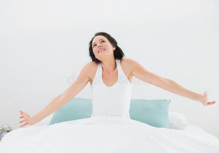 年轻女子在床上伸展双臂