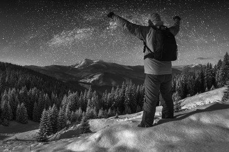 徒步旅行者反对布满星星的夜空。黑色和白色