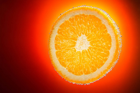 新鲜的橙片橙色渐变背上泡沫水中