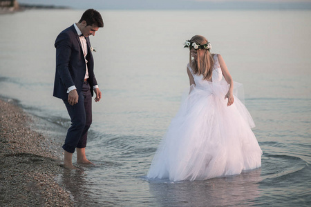 新娘和新郎在日落海上行走，浪漫的已婚夫妇