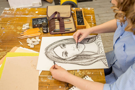 年轻姑娘做天然木炭在纸上素描