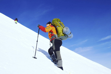 冬季徒步旅行。在山里徒步旅行带着背包和帐篷雪的冬天