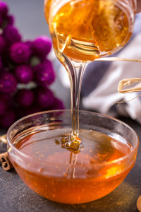 新鲜的蜂蜜滴在桌上的玻璃碗