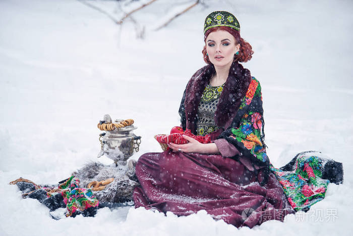 在苹果与茶炊一冬天下雪天强的霜的俄罗斯风格的华丽年轻女子肖像连买
