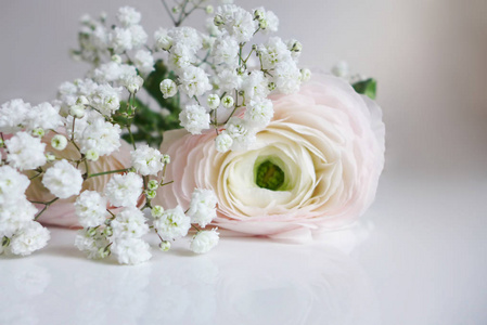 特写的婚礼花束由波斯毛茛 花毛茛和躺在桌子上的白色宝宝呼吸满天星花
