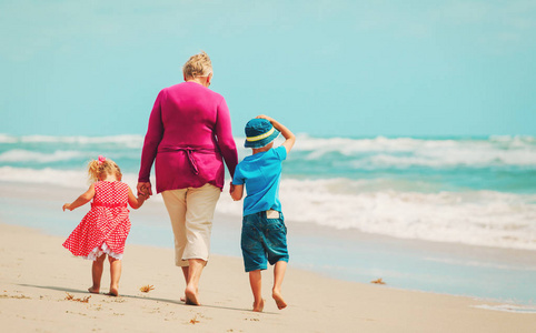 快乐祖母与孩子小男孩和女孩在海滩