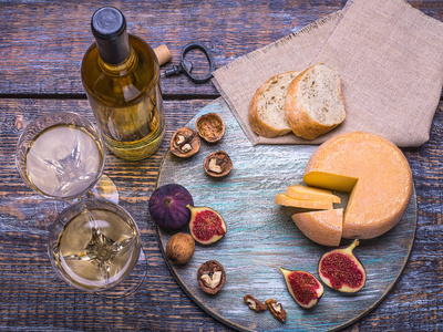 白红酒一瓶 软木 瓶螺杆和一套产品奶酪 葡萄 坚果 橄榄 无花果上一块木板，在背景