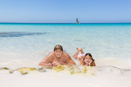 快乐的男孩和小女孩放松, 游泳和享受那里的休闲时间和热带美丽的海滩