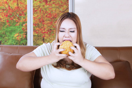贪婪的肥胖女人享受一个汉堡包图片