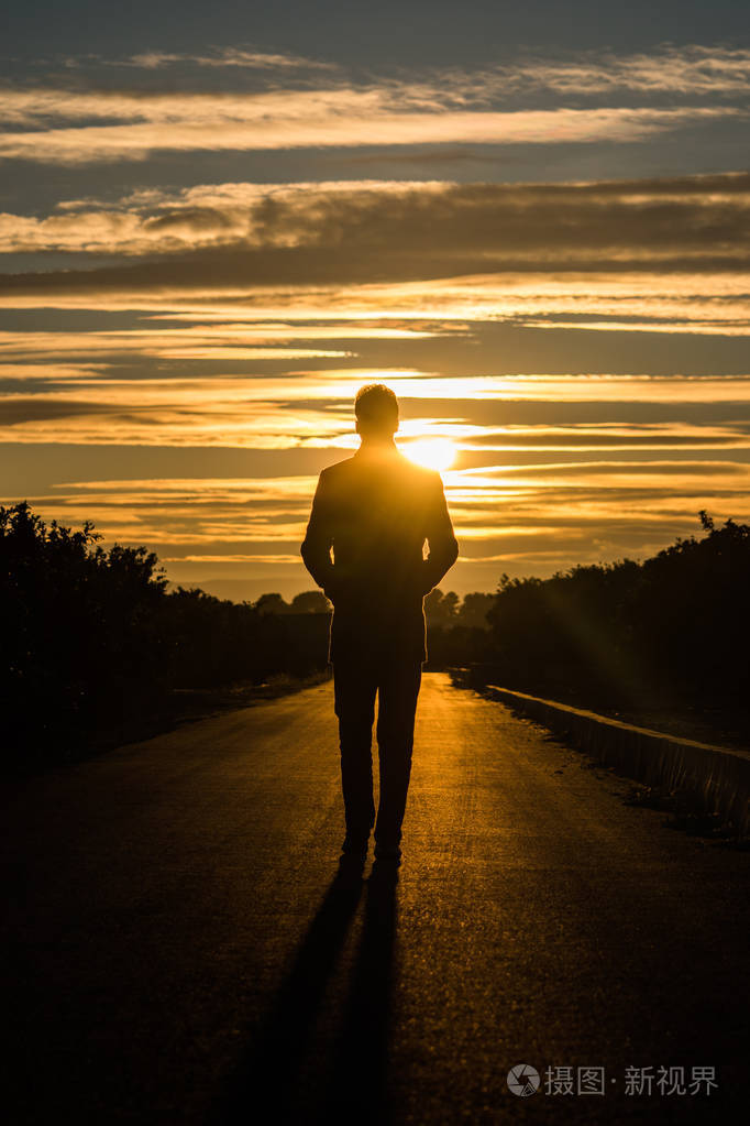 一个人走在路上,在日落时分的轮廓