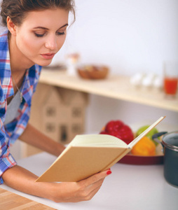 年轻女人阅读食谱在厨房里寻找食谱
