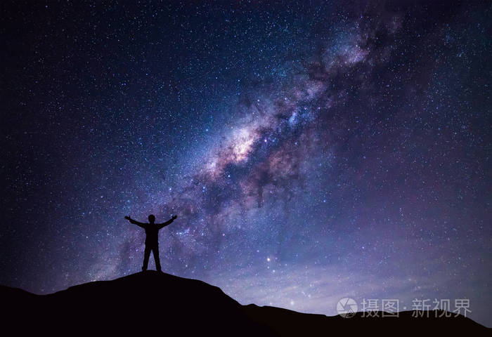 银河景观.快乐的人,站在山与夜晚的天空和明亮的星星,在背景上的剪影