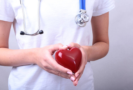 女性医学医生手中握着红色的玩具的心和听诊器头。有氧运动运用，学生教育，医生让心脏物理 率措施，心律失常概念