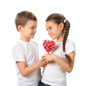男孩给一个小女孩糖果心形红色棒棒糖白色孤立。情人节那天。孩子们的爱