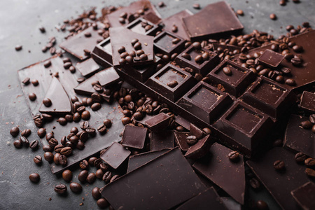 咖啡与巧克力黑巧克力豆。巧克力的断的片。巧克力碎片。一大块巧克力灰色抽象背景。咖啡豆