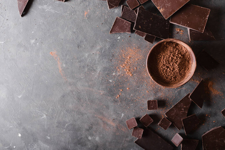 巧克力块和可可粉。巧克力碎片。一大块巧克力灰色抽象背景。与巧克力的背景。片的巧克力