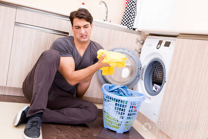 年轻的男人洗衣服在家里
