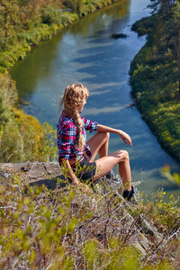 年轻的金发女子旅游坐在山崖上的锡伯文的背景