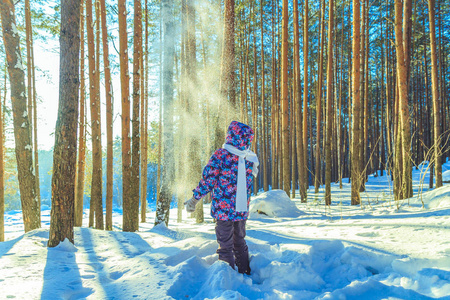 女孩抛雪在阳光灿烂的冬天森林