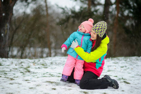 年轻女子带着小女儿在冬季公园散步