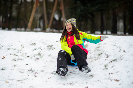 年轻女子高高兴兴地向下移动从一座小山在飞碟雪橇上