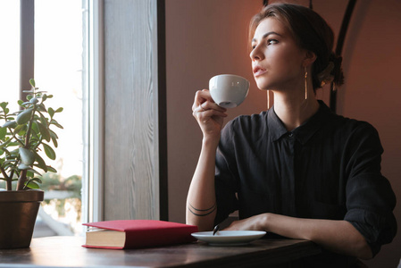 年轻漂亮的女人在咖啡馆喝咖啡