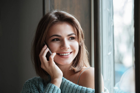 性格开朗的年轻女子坐在靠近窗口的电话交谈