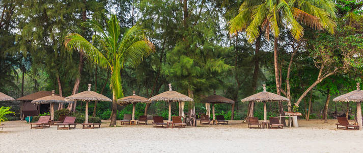 木椅和白色海滩上的遮阳伞