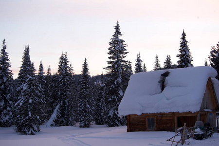 传统的老木结构房子在冬天在日落背景
