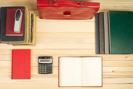 木制的桌子上的书籍，文档，计算器，红色公文包